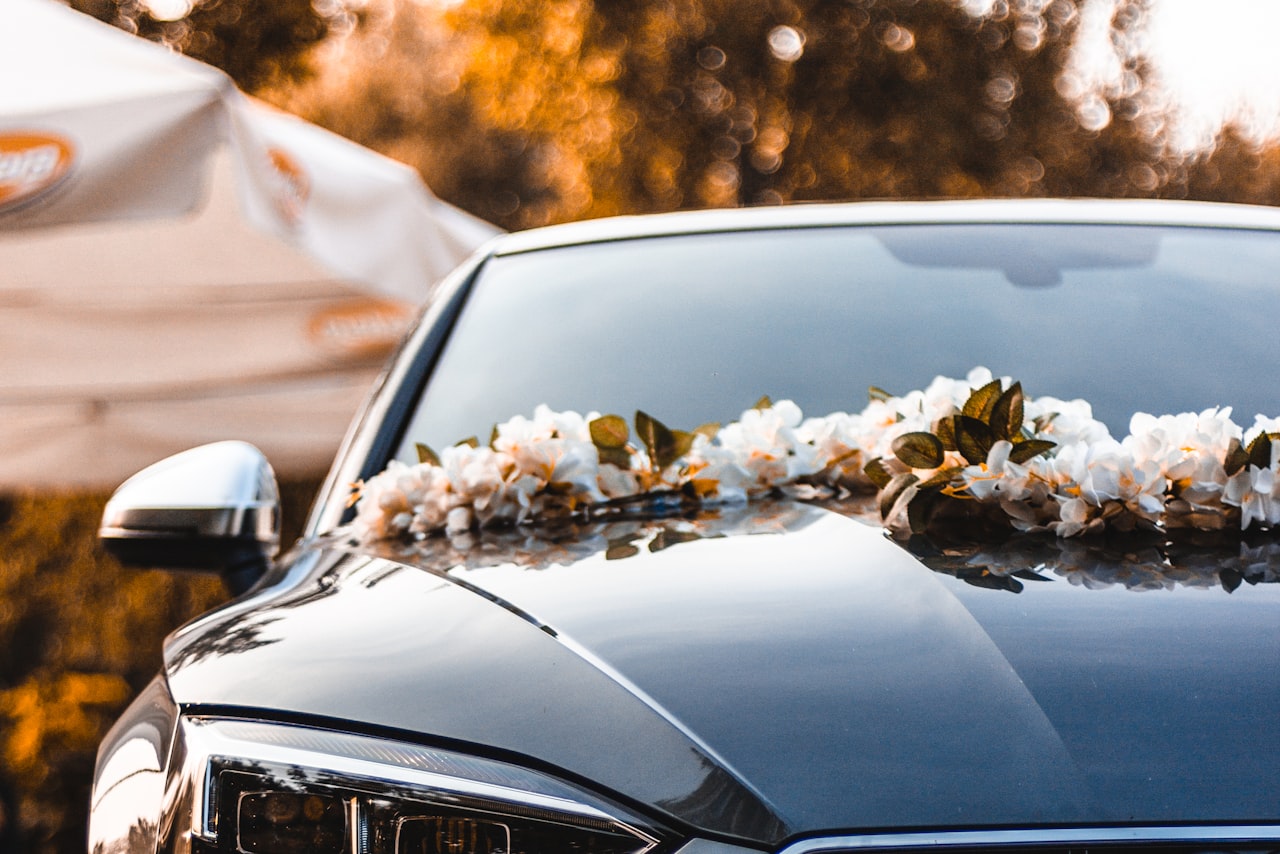 Newlywed couple beside a luxury car